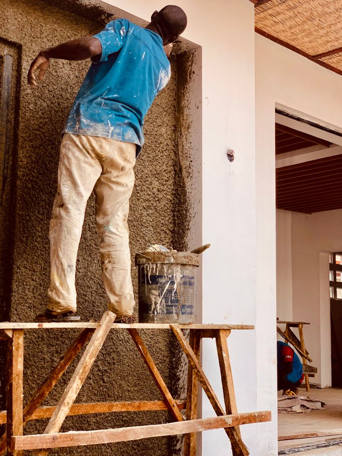 Hardworking construction worker plastering a wall in Kaduna, Nigeria.