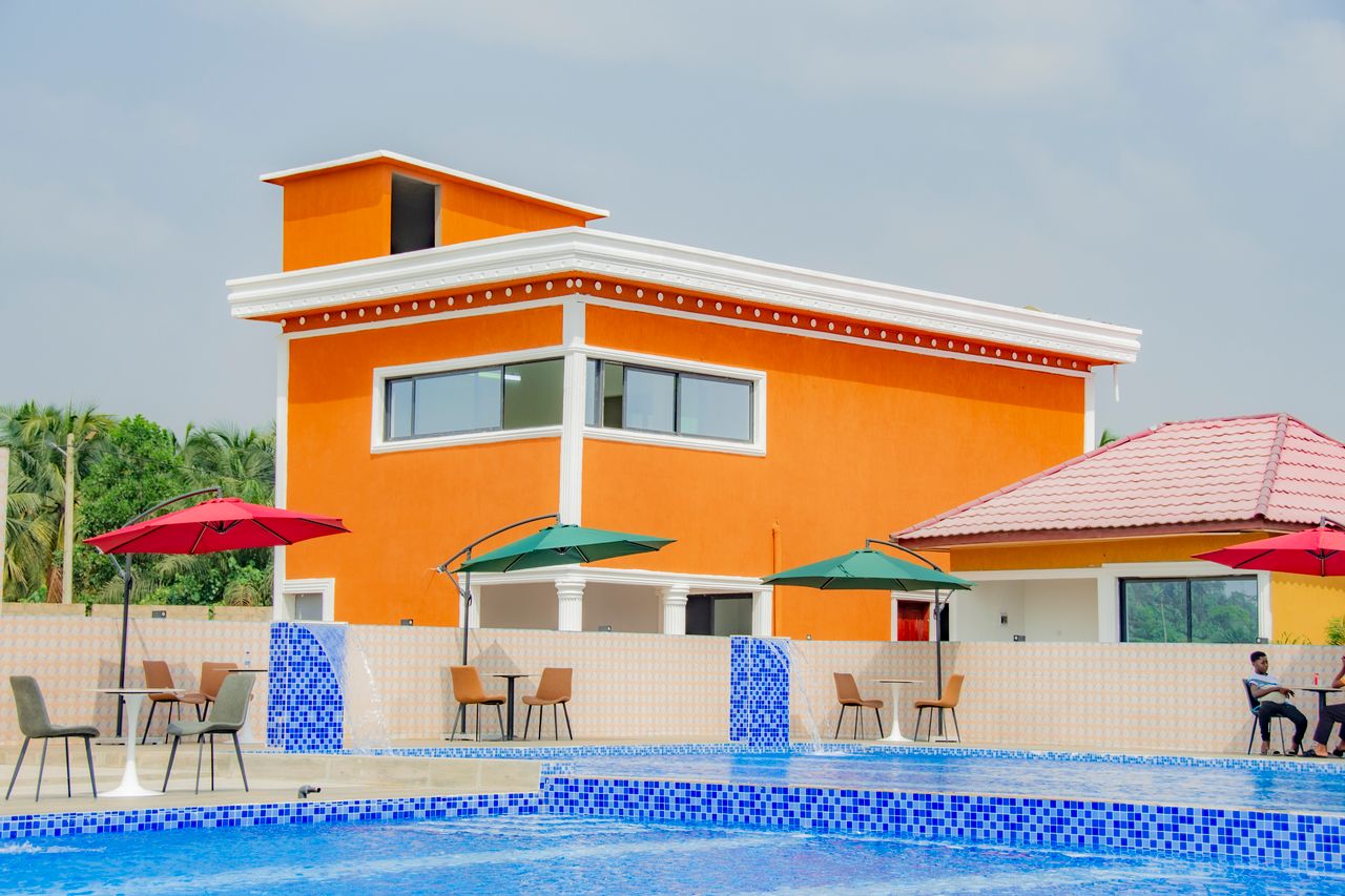 Modern orange villa with a luxurious poolside setting, perfect for relaxing in Bonoua, Côte d'Ivoire.